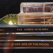 A stack of CD albums that reveals their sides, the two labeled are Pink Floyd's "Dark Side of the Moon" and R.E.M.'s "Automatic for the People"